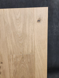 Beckham Brothers’ New York Loft White Oak-Hardwood panel features visible grain and knots on a dark textured background.