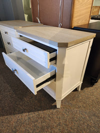 The Magnussen B6310- Echo Isles Night Stand with two drawers is displayed on carpet in a furniture showroom.
