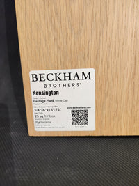 Label on wood sample shows "Beckham Brothers Heritage Plank White Oak" hardwood flooring details and a QR code.