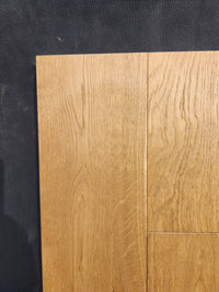 Close-up of Beckham Brothers Heritage Plank White Oak flooring panels on a dark textured surface.