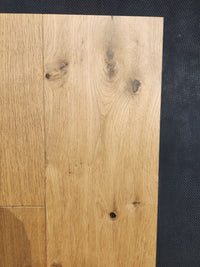 Heritage Plank White Oak by Beckham Brothers shown with visible knots and grain on a dark textured background.