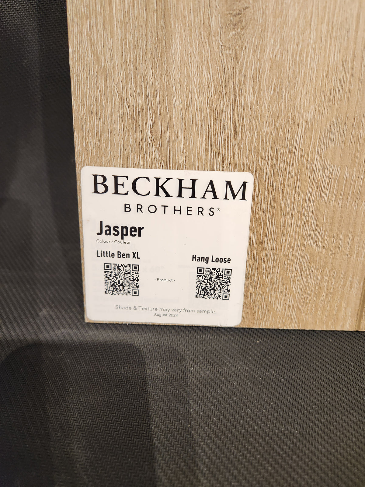 A sample "Little Ben XL Luxury Vinyl" plank by Beckham Brothers with QR codes sits on a textured surface.