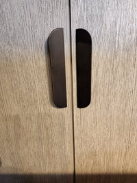 Close-up of two vertical handles on Magnussen D5878 Tristan LT. Brown Dining Cabinet with light wood grain doors.