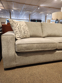 The Decor-rest 2456 3-Piece Sectional, gray and customizable, features a patterned accent pillow in a chic showroom.