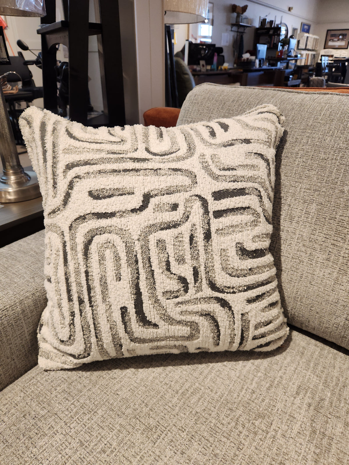 A square, textured pillow with a geometric pattern sits on the Decor-rest 2456 3-Piece Sectional in the showroom.