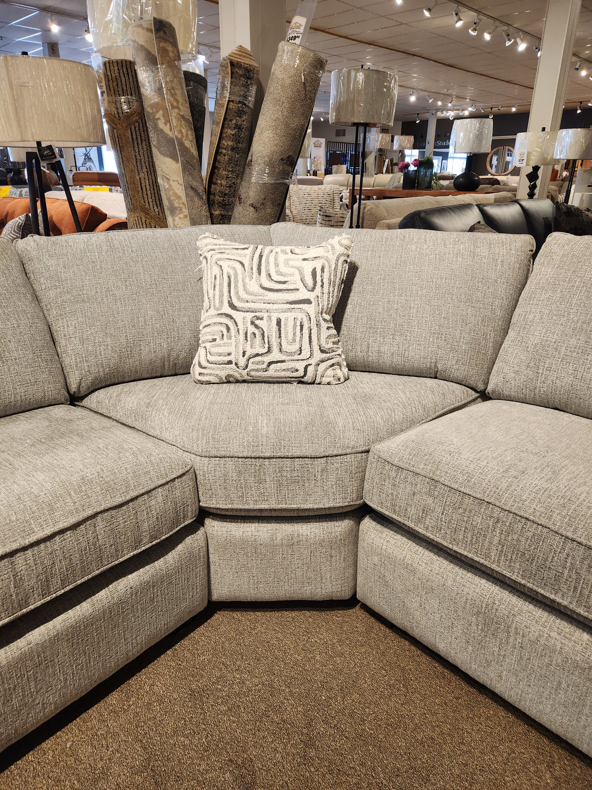 The Decor-rest 2456 3-Piece Sectional with a decorative pillow is showcased in a showroom with lamps and rugs.