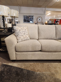 The Superstyle 5101 Sofa in beige with a patterned pillow provides ergonomic seating next to a black side table and lamps.