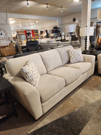Superstyle 5101 Sofa in light beige with ergonomic seating and two patterned pillows, displayed in-store.