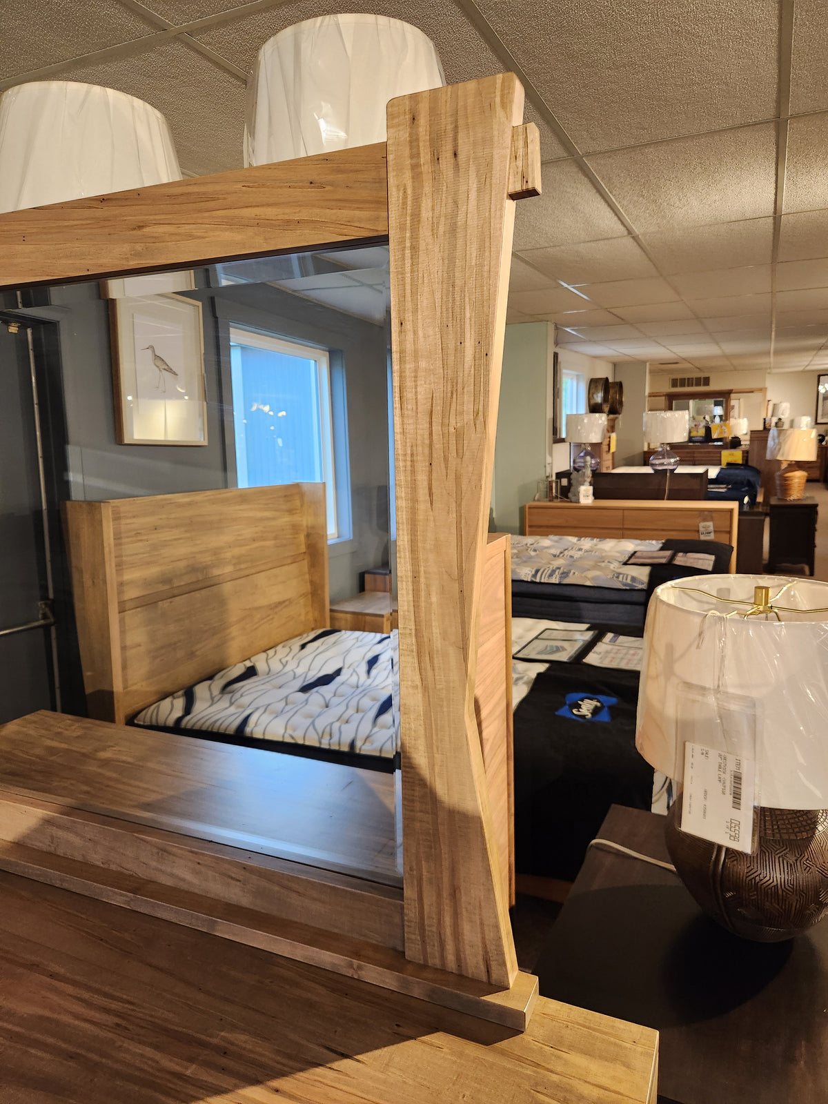 The Handstone JA9 Dresser Mirror is displayed among beds and lamps in the furniture showroom.