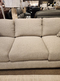 The Donald Choi Laguna Sofa features beige upholstery and a high-density foam seat, shown with couches and lamps in-store.