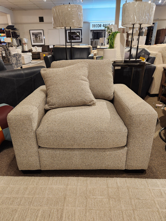 Donald Choi Laguna Chair: Beige upholstered armchair with square arms and matching pillow in a modern showroom.