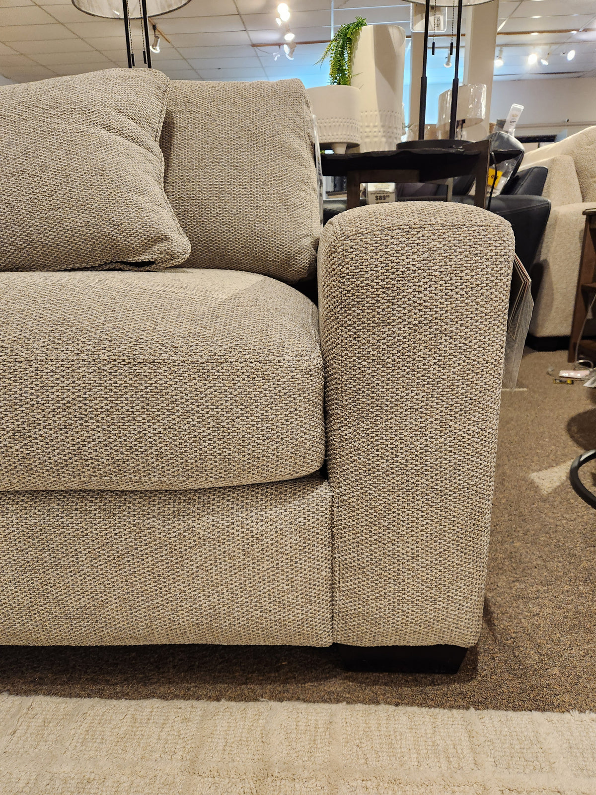 Close-up of the Laguna Chair by Donald Choi, featuring a granite finish arm and matching cushion in a showroom.