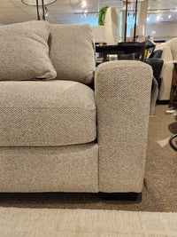 Close-up of the Laguna Chair by Donald Choi, featuring a granite finish arm and matching cushion in a showroom.
