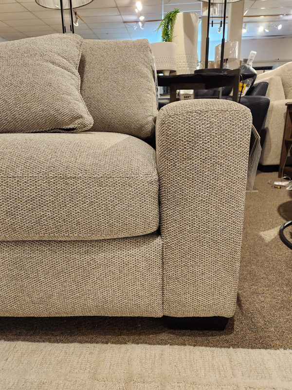 Close-up of the Laguna Chair by Donald Choi, featuring a granite finish arm and matching cushion in a showroom.