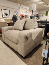 Donald Choi Laguna Chair in beige with two cushions, displayed under bright lights for a modern granite finish look.