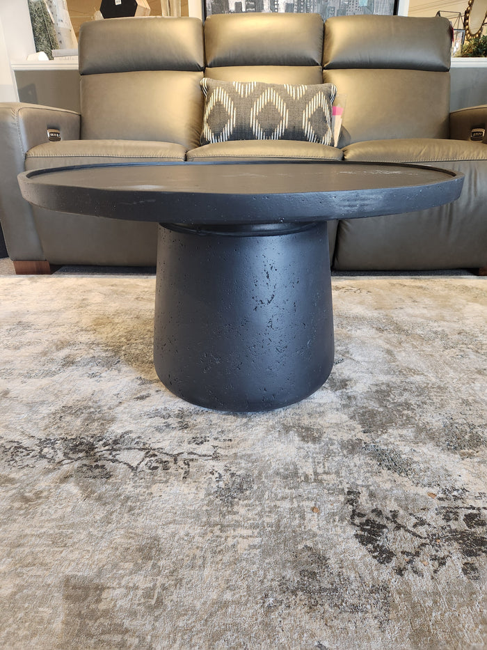 Maru 32" Coffee Table by Donald Choi on a textured rug in front of a gray leather sofa with a patterned pillow.