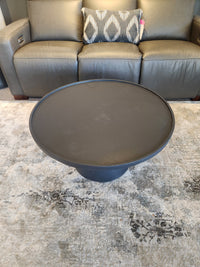 The Maru 32" Coffee Table by Donald Choi sits on a patterned rug in front of a gray sofa with a decorative pillow.