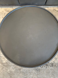 The Maru 32" Coffee Table by Donald Choi, round and gray concrete, sits near a dark sofa on a beige floor.