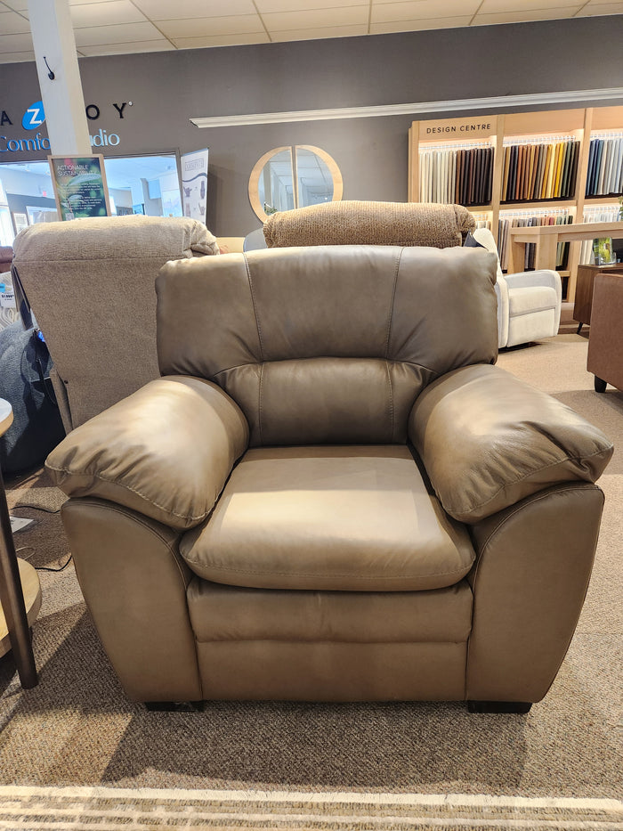 The Palliser 77343 Amisk Chair is shown in a showroom with lounge seating and fabric samples in the background.