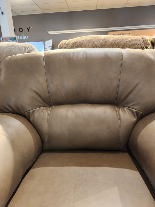 Close-up of the Palliser 77343 Amisk Chair in taupe leather, highlighting stitching and lounge seating in a showroom.