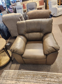 The Palliser 77343 Amisk Chair in brown leather is displayed with lounge seating and a round wooden table.