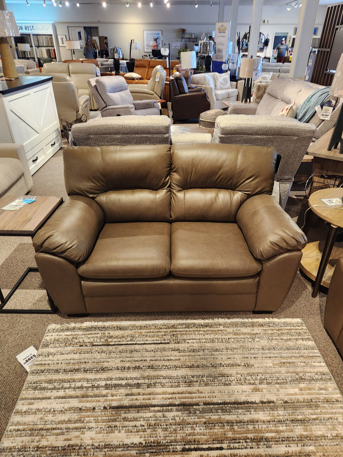 Palliser 77343 Amisk Loveseat in brown leather with high-resiliency foam sits behind a striped area rug.