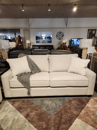 The Decor-rest 2981 Sofa features box seat cushions, two patterned pillows, and a gray throw blanket on display.