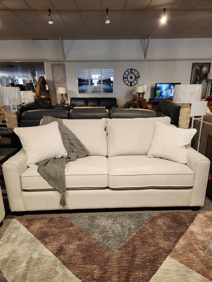 The Decor-rest 2981 Sofa features box seat cushions, two patterned pillows, and a gray throw blanket on display.