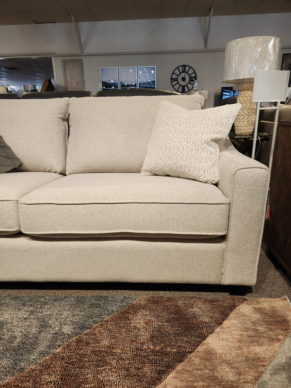 The Decor-rest 2981 Sofa, a beige modern style with box cushions and a patterned pillow, is shown in the showroom.