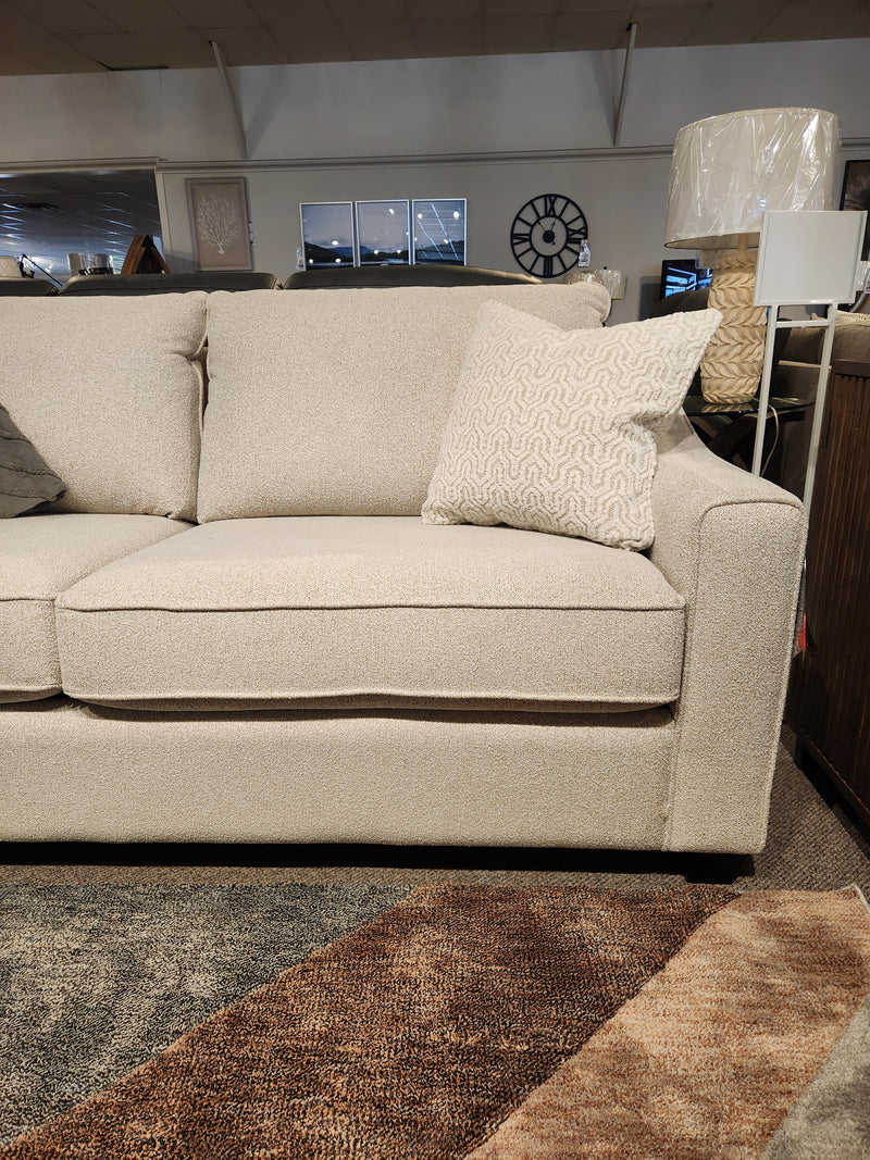 The Decor-rest 2981 Sofa, a beige modern style with box cushions and a patterned pillow, is shown in the showroom.