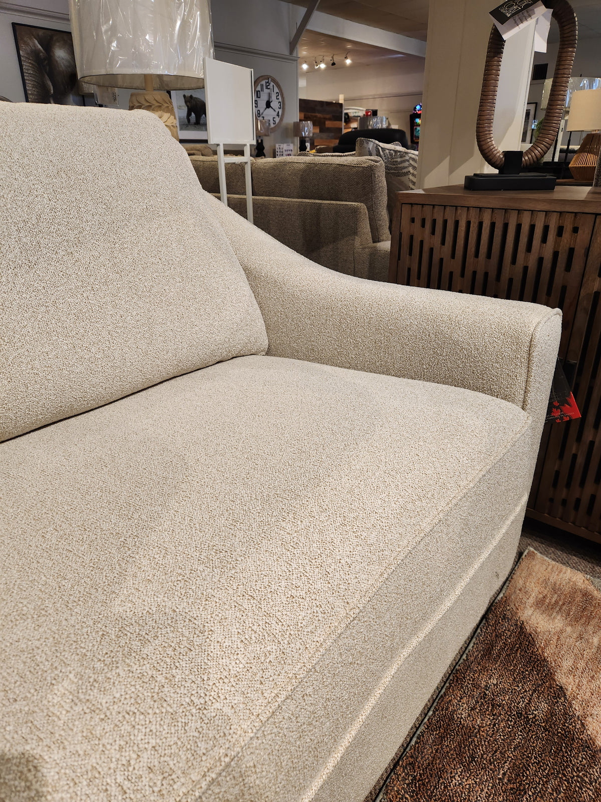 Close-up of the Decor-rest 2981 Sofa in beige, featuring box seat cushions beside a wooden cabinet in a showroom.