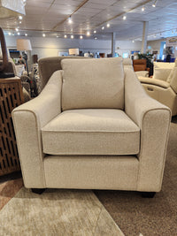 The Decor-rest 2981 Chair, beige upholstered with box seat cushions and square arms, is on display in the showroom.