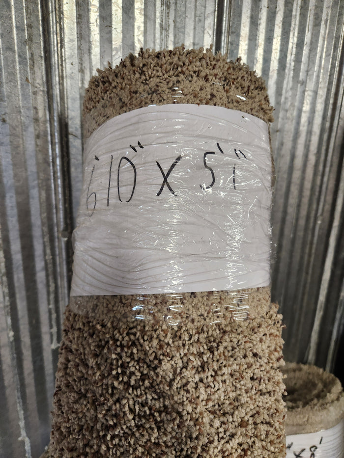 A Flooring CLEARANCE Carpet Remnant 6'10" x 5'1" leans against a corrugated metal wall.