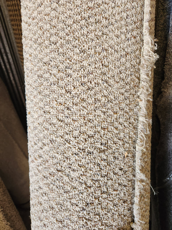 Close-up of Flooring CLEARANCE Carpet Remnant 8'10" x 4'10", low pile tan with textured surface and frayed right edge.