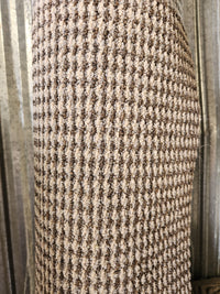 A close-up of a Flooring CLEARANCE Carpet Remnant 7' X 8', rolled and upright against a corrugated metal wall.