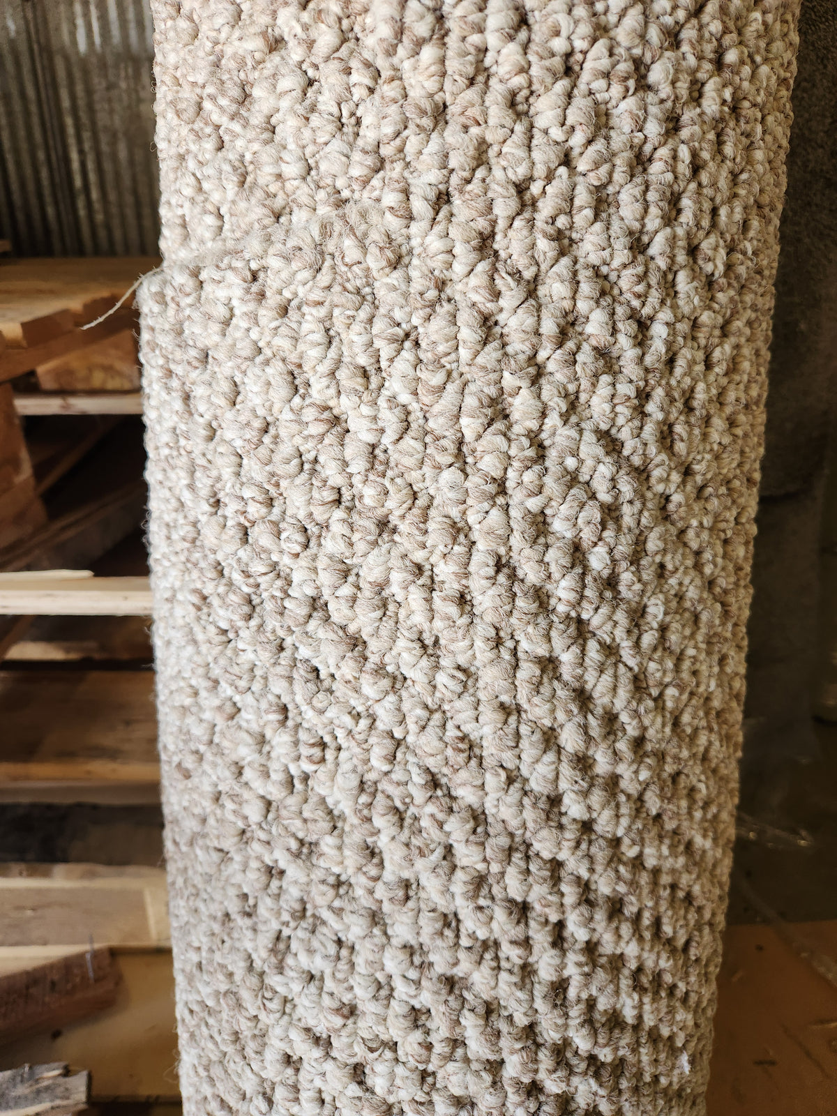 A Carpet Remnant 12' X 3'9" by Flooring CLEARANCE stands rolled up next to stacked wooden pallets.