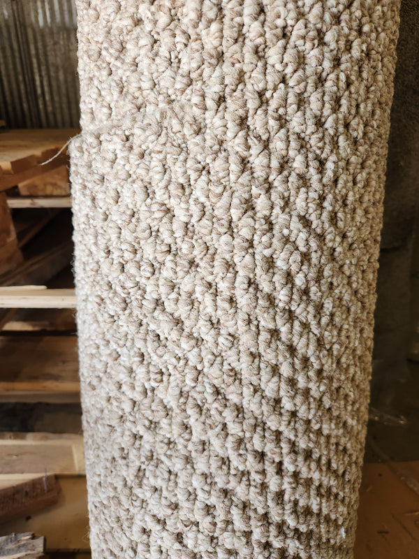 A Carpet Remnant 12' X 3'9" by Flooring CLEARANCE stands rolled up next to stacked wooden pallets.