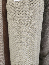 A close-up of Flooring CLEARANCE's Carpet Remnant 17'6" x 4'9", a beige, looped low-pile roll displayed upright.