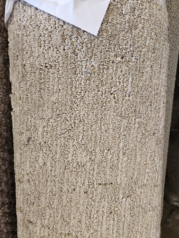 Close-up of a beige Flooring CLEARANCE Carpet Remnant 12' X 4' with white paper resting on top.