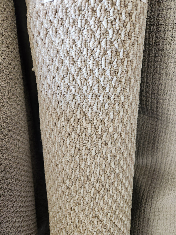 A close-up of Flooring CLEARANCE Carpet Remnant 5' X 7', light beige with visible low pile looped fibers, rolled upright.