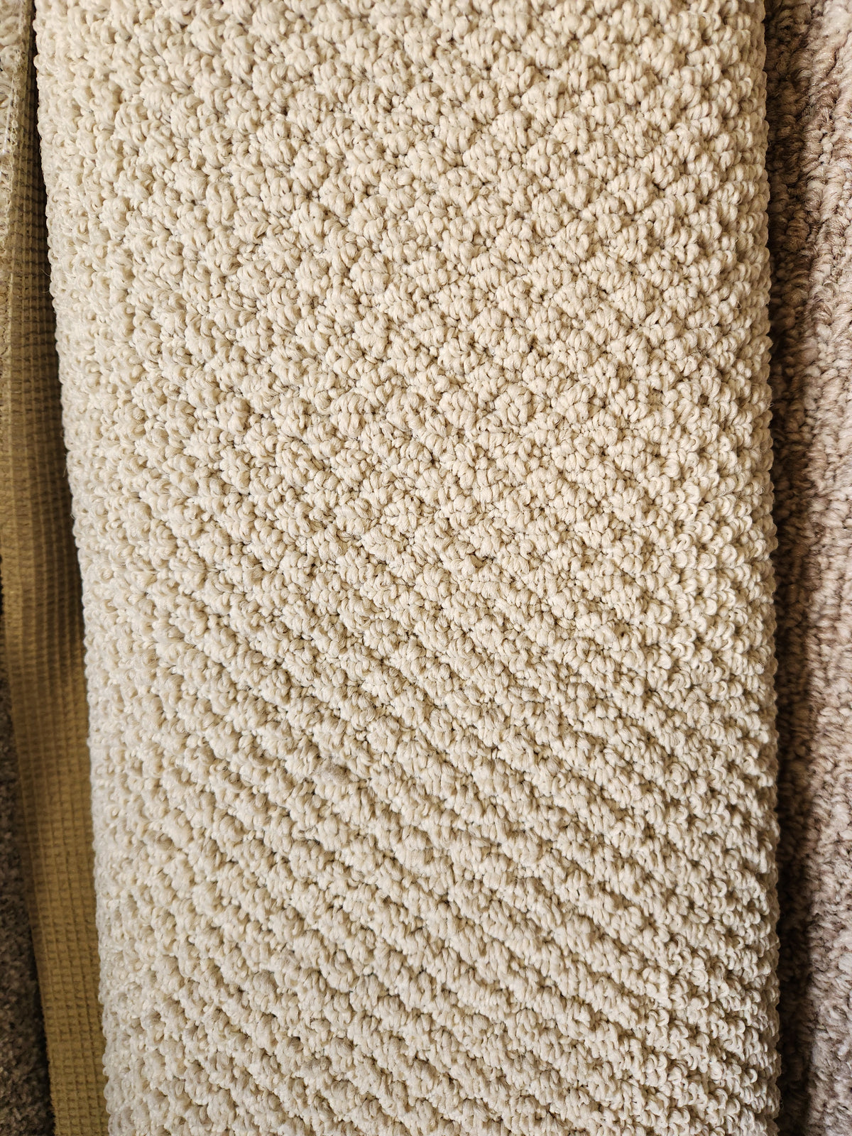 Close-up of Flooring CLEARANCE Carpet Remnant 6' X 8'7" in beige, low pile with a diamond pattern among samples.