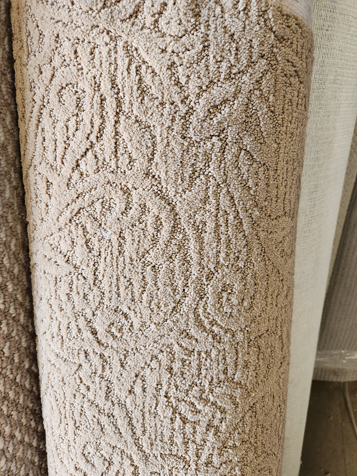 Close-up of a Flooring CLEARANCE Carpet Remnant 5' X 13' in tan, with another Bohemian rug roll in the background.