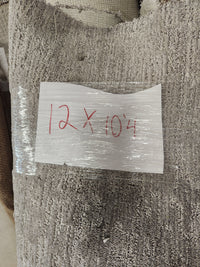 A "Carpet Remnant 12' X 10' 4"" by Flooring CLEARANCE is labeled with a handwritten sign on a light gray rug.