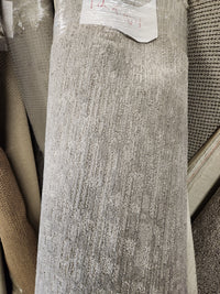 A Flooring CLEARANCE Carpet Remnant 12' X 10'4" in gray low pile stands among other rolls in store.