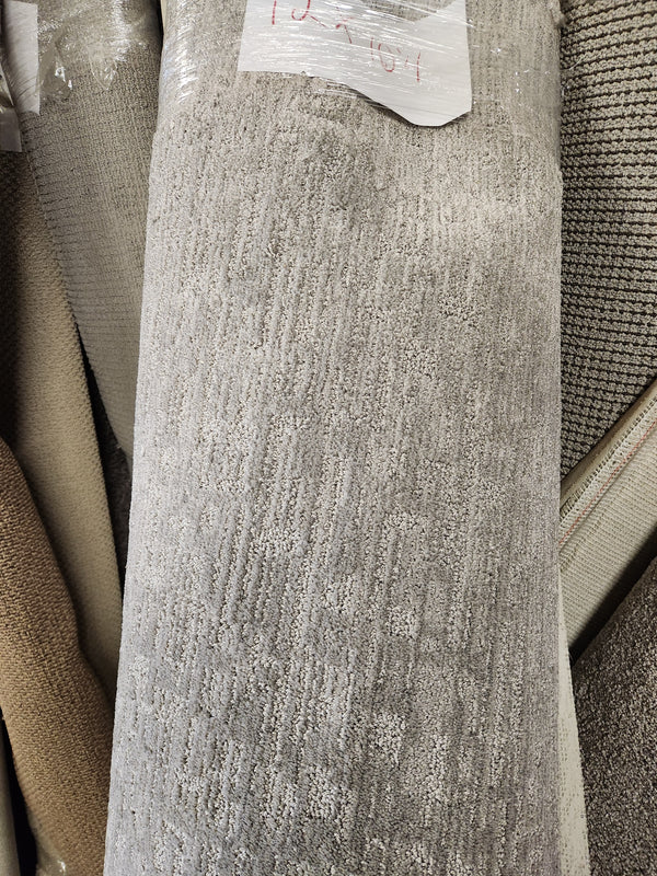 A Flooring CLEARANCE Carpet Remnant 12' X 10'4" in gray low pile stands among other rolls in store.