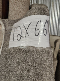 A Flooring CLEARANCE Carpet Remnant 12' x 6'6" in beige and medium pile is wrapped in plastic in storage.