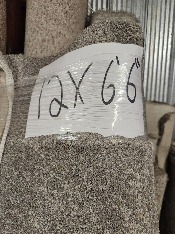 A Flooring CLEARANCE Carpet Remnant 12' x 6'6" in beige and medium pile is wrapped in plastic in storage.