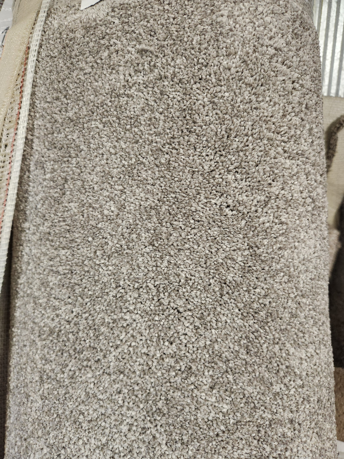 A close-up of Flooring CLEARANCE's Carpet Remnant 12' X 6'6", a light brown, medium pile rug with dense fibers.
