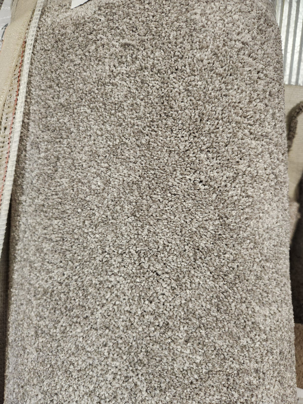 A close-up of Flooring CLEARANCE's Carpet Remnant 12' X 6'6", a light brown, medium pile rug with dense fibers.