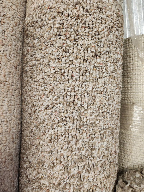 Close-up of Flooring CLEARANCE Carpet Remnant 6'10" X 9'6" with low loop pile, shown rolled near a woven rug.